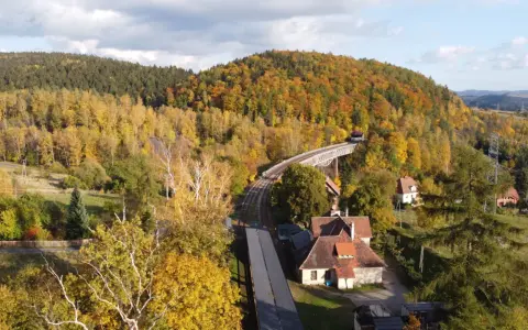 Jesienna panorama Gór Sowich. Widok na most kolejowy, tory i domy wśród kolorowych drzew. Atrakcje turystyczne regionu.