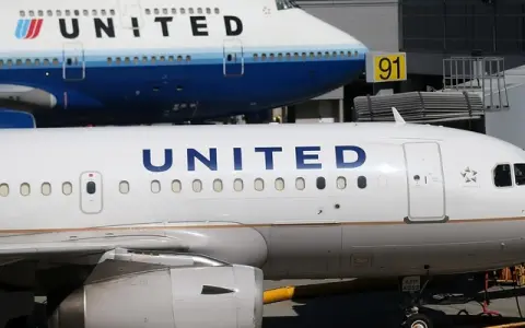 Dwa samoloty United Airlines na płycie lotniska. Jeden z nich to Boeing 747, drugi to mniejszy samolot. W tle widać budynek terminala.