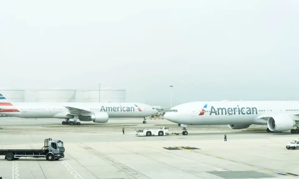 Dwa samoloty American Airlines na płycie lotniska, gotowe do przyjęcia bagażu rejestrowanego.
