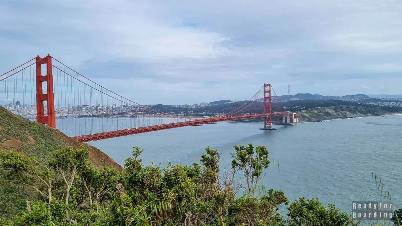 Widok na most Golden Gate w San Francisco, z zielonymi wzgórzami i błękitną wodą.