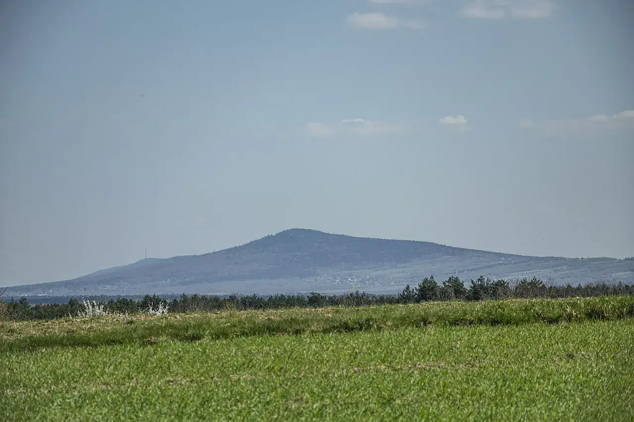 Łagodne zbocza gór świętokrzyskich w oddali, na pierwszym planie zielona łąka.
