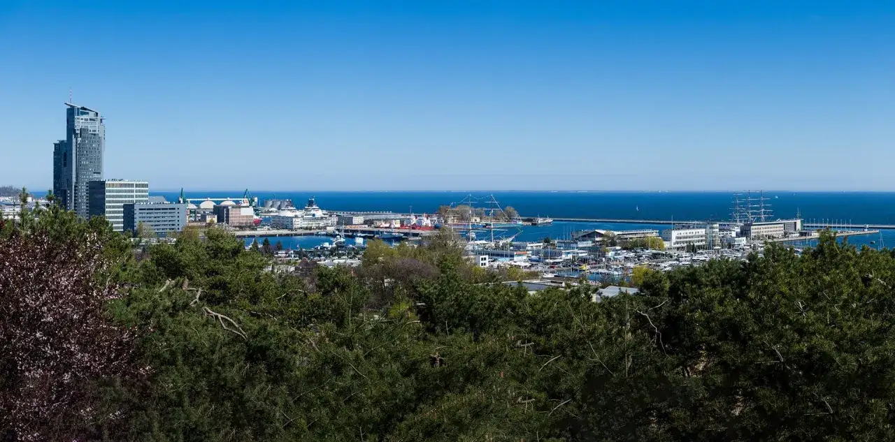 Gdynia co zobaczyć: panorama portu z żaglowcami, nowoczesnymi budynkami i zielenią.