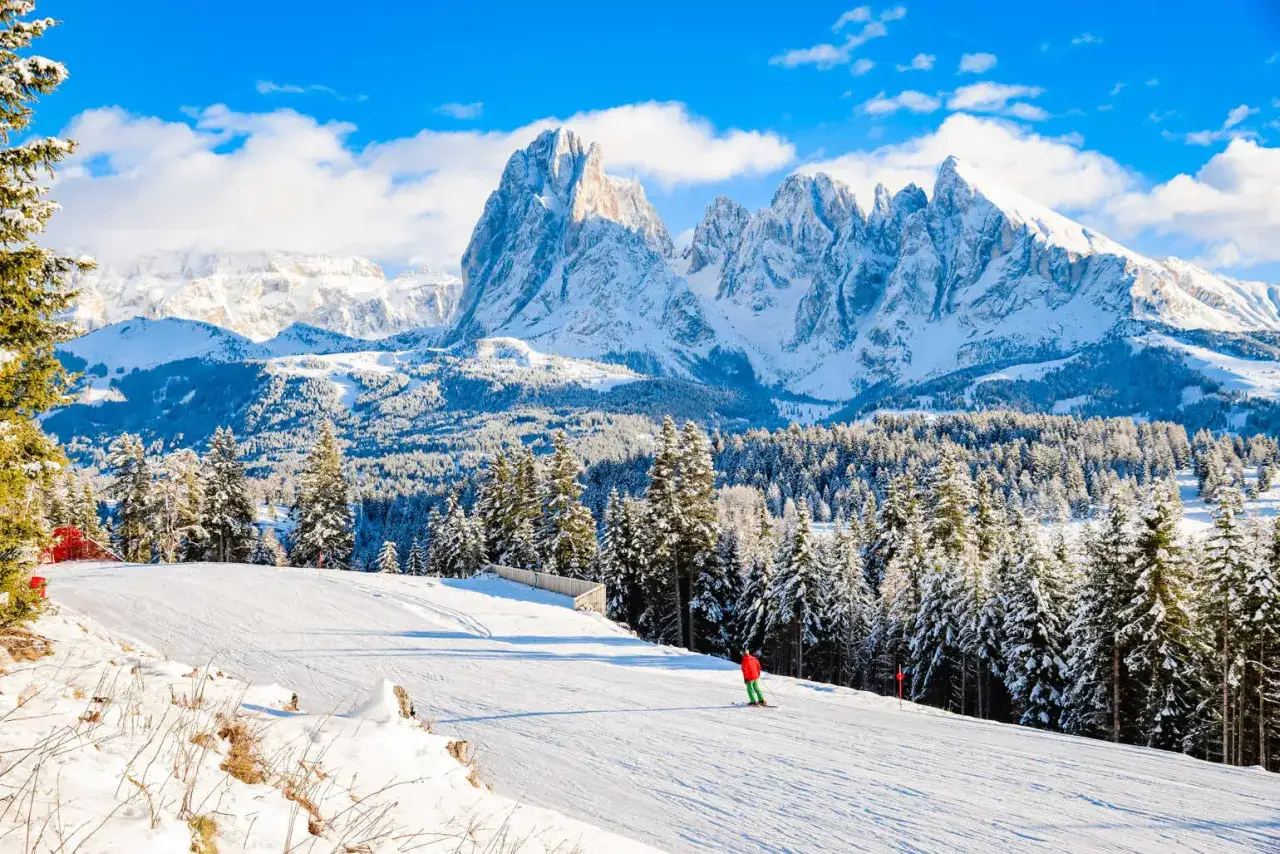 Włochy narty gdzie? Widok na ośnieżone szczyty Dolomitów i narciarza na stoku.