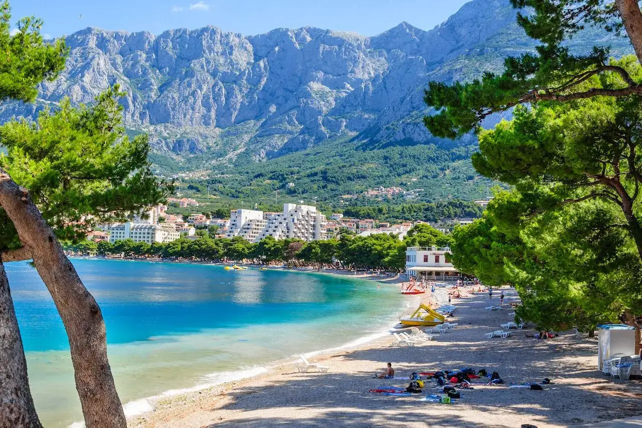 Malownicze miasta w Chorwacji nad morzem, z plażą, turkusową wodą i górami w tle.