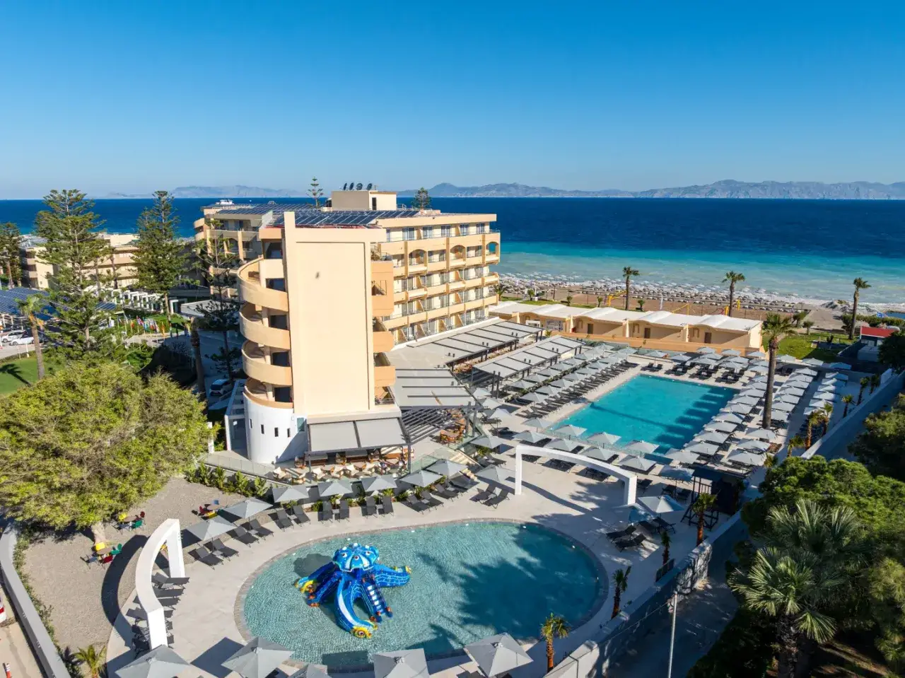 Luksusowy hotel z basenami i zjeżdżalnią, tuż przy plaży na Rodos. Idealne miejsce na wakacje pod parasolem.