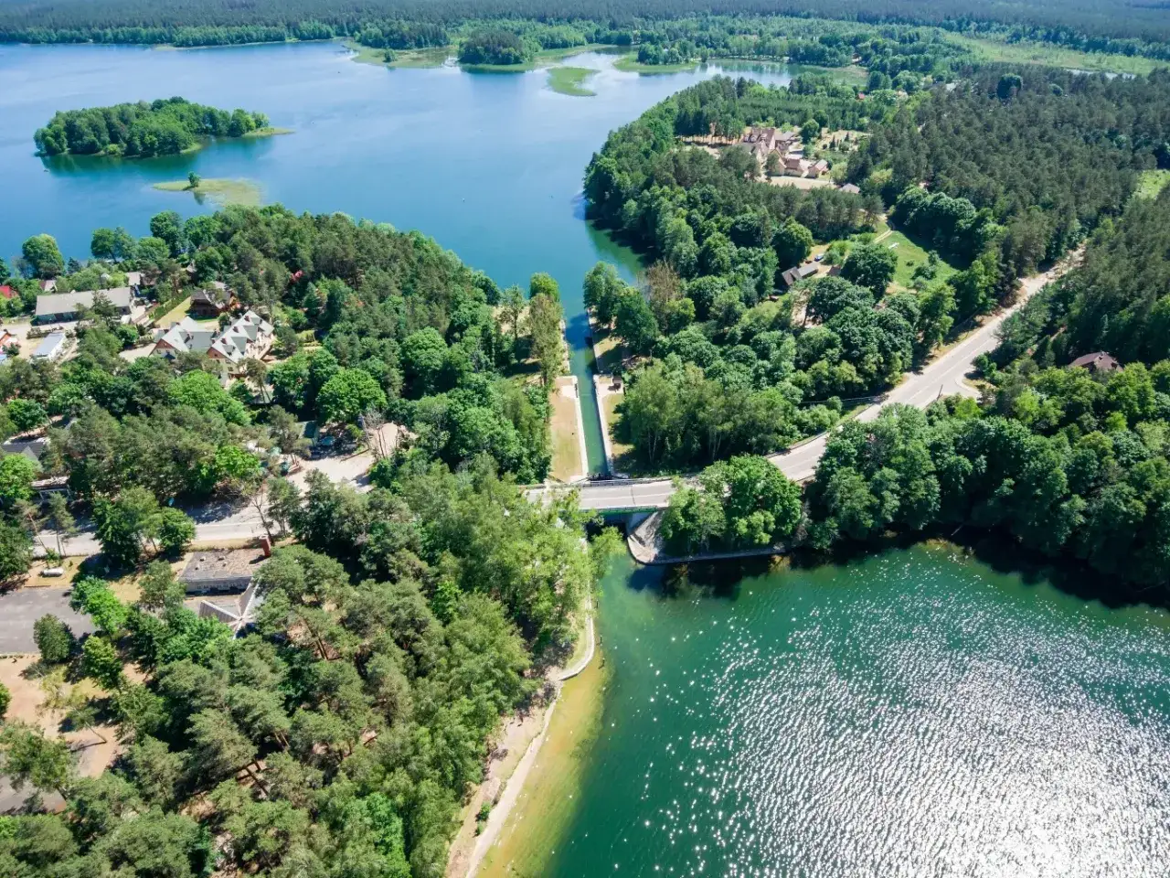 Malowniczy widok na jezioro, które jest najczystsze w Polsce. Woda lśni, otoczona lasami i domkami.