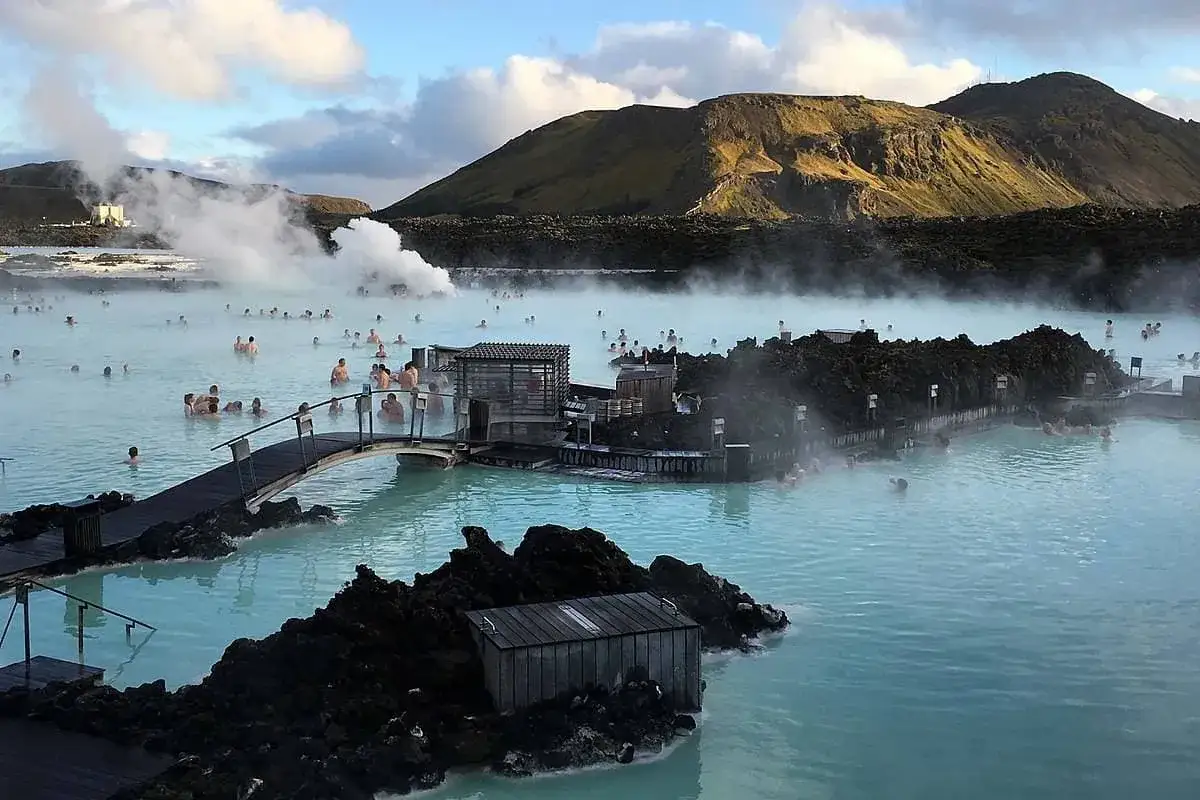 Relaks w Blue Lagoon Islandia. Ludzie kąpią się w geotermalnych wodach, otoczeni wulkanicznym krajobrazem i parą unoszącą się nad powierzchnią.