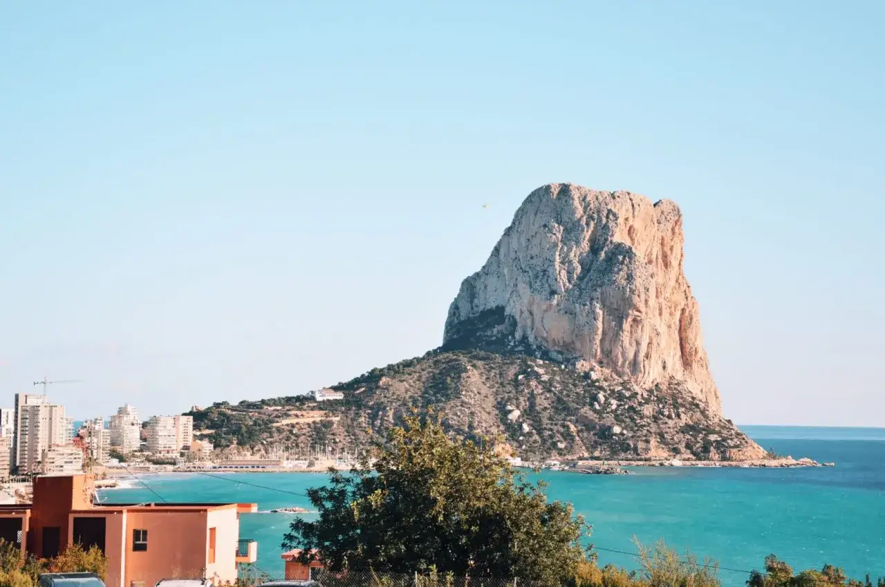 Imponujący klif Peñón de Ifach, jedna z głównych costa blanca atrakcje, góruje nad turkusowym morzem i nadmorskim miasteczkiem.