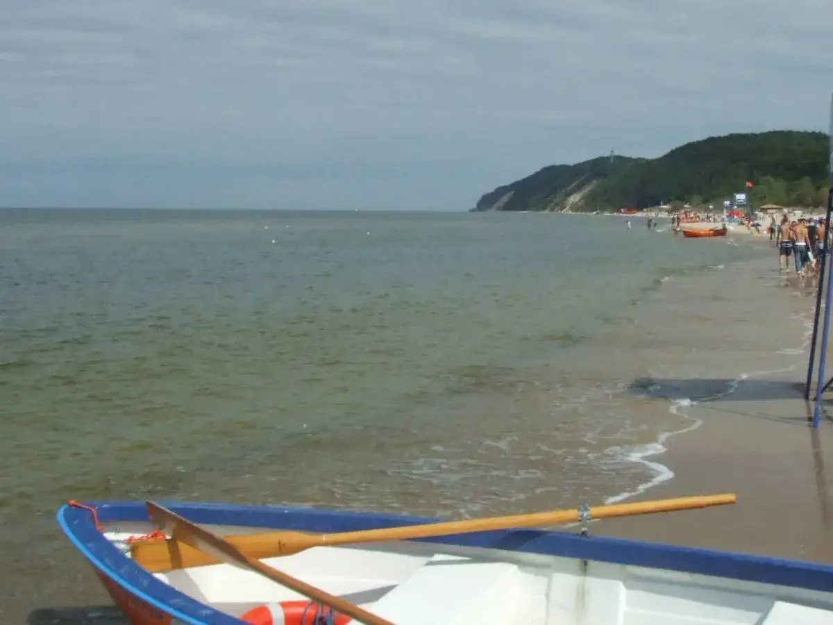 Łódka na plaży, morze i wzgórza. Pomorze Zachodnie atrakcje oferuje piękne widoki i wypoczynek nad Bałtykiem.