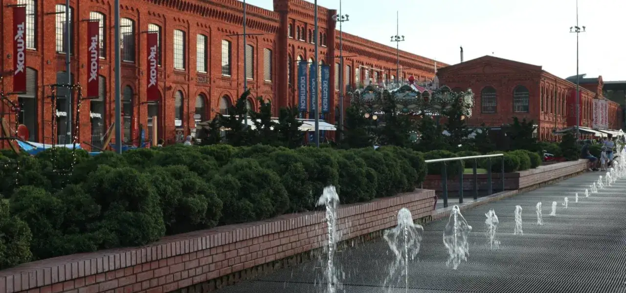 Łódź: ceglane budynki postindustrialne, karuzela, fontanny i zieleń tworzą atrakcje turystyczne.