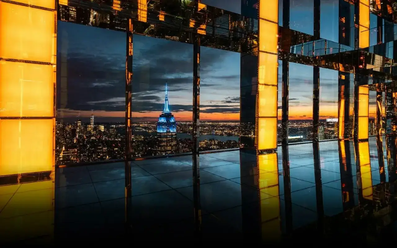 Widok na nocny Nowy Jork z Empire State Building, widziany przez lustrzane ściany Summit One Vanderbilt.